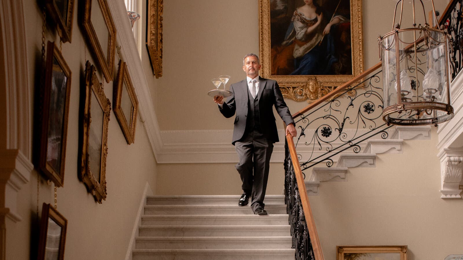 Butler in formele kledij met dienblad op een klassieke trap